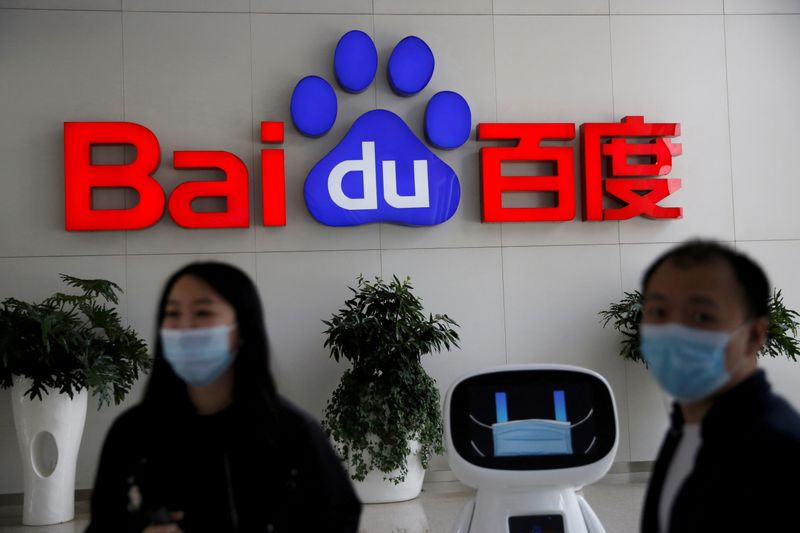 &copy; Reuters. FILE PHOTO: Employees wearing face masks are seen next to a Baidu AI robot, in front of a sign of Baidu at the company&apos;s headquarters in Beijing