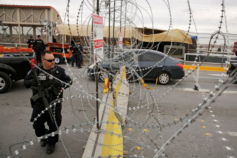 © Reuters. Un agente de Aduanas y Protección Fronteriza de EEUU protege la entrada de la frontera mientras la gente hace cola para entrar al país en el cruce fronterizo Paso del Norte, visto desde Ciudad Juárez, México.