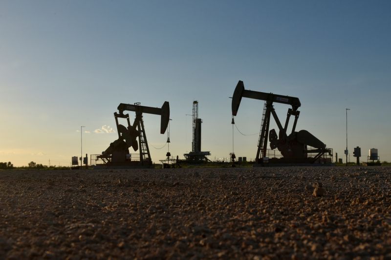 © Reuters. Pompe petroifere davanti a una piattaforma di perforazione in un giacimento petrolifero a Midland, Texas,