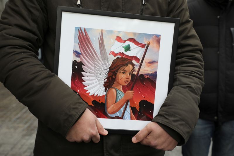 &copy; Reuters. A person holds a picture depicting a child who was killed during the Beirut port explosion, at a protest, after a Lebanese court removed the judge leading the investigation into the explosion, outside the Justice Palace in Beirut
