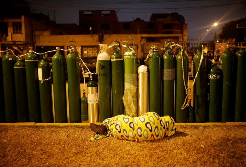 &copy; Reuters. Pessoa dorme ao lado de cilindros vazios de oxigênio para guardar lugar na fila de reabastecimento em Callao, no Peru