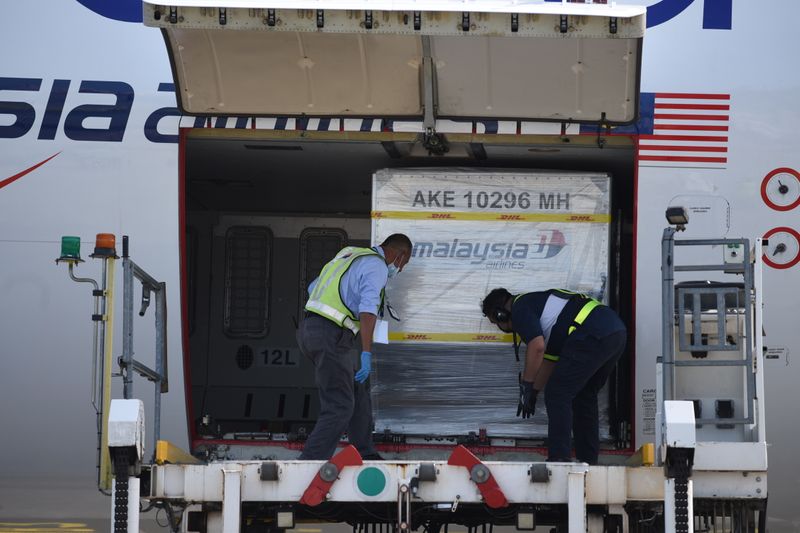 &copy; Reuters. Containers carrying the first batch of Pfizer-BioNTech COVID-19 vaccines are unloaded from a plane at the MASkargo Complex in Sepang