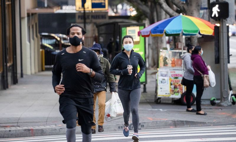 © Reuters. People wearing personal protective face masks jog downtown during the outbreak of the coronavirus disease (COVID-19), in Los Angeles