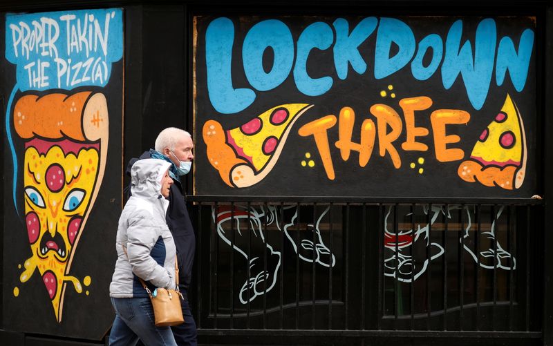 &copy; Reuters. People walk past a mural amid the outbreak of the coronavirus disease (COVID-19) in Manchester