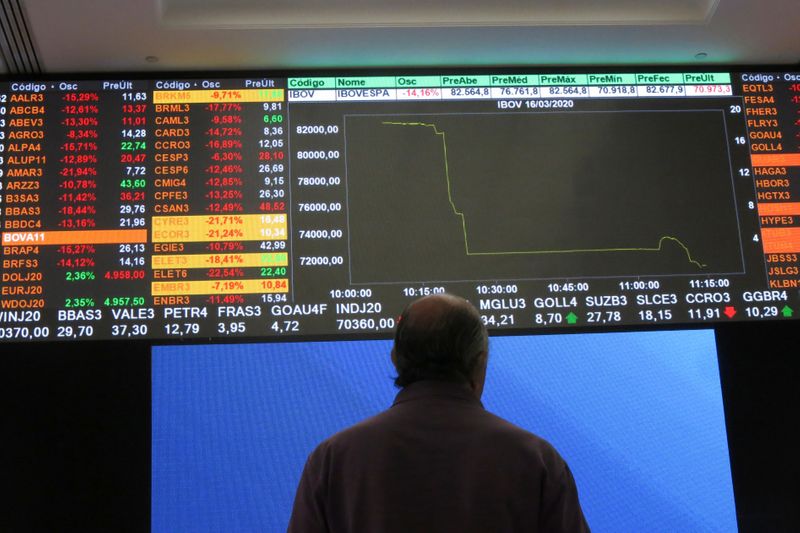 © Reuters. A man stands in front of an electronic display at B3 Brazilian Stock Exchange after an automatic circuit breaker was triggered this morning, in Sao Paulo