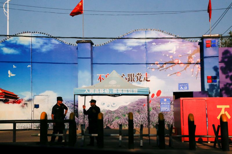 © Reuters. FILE PHOTO: Security guards stand at the gates of what is officially known as a vocational skills education centre in Huocheng County