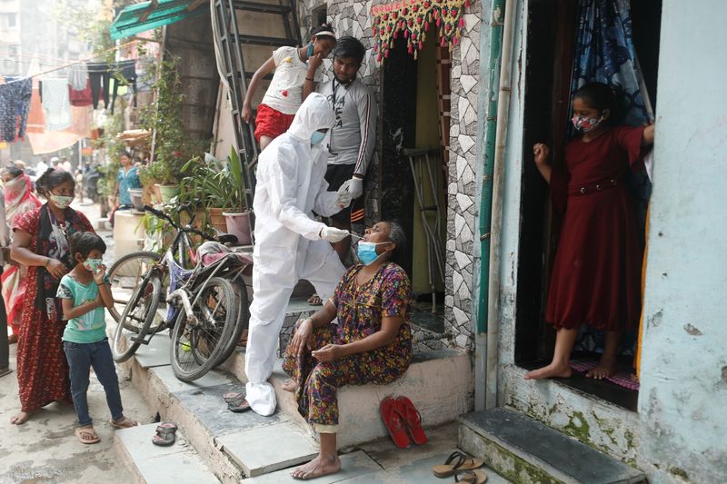 &copy; Reuters. Profissional de saúde com máscara e trajes de proteção colhe amostra em paciente para exame de detecção de coronavírua em Mumbai