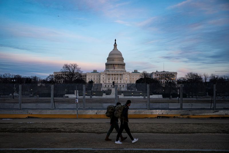 &copy; Reuters. People walk past protective fencing surrounding the U.S. Capitol, as the sun sets in Washington