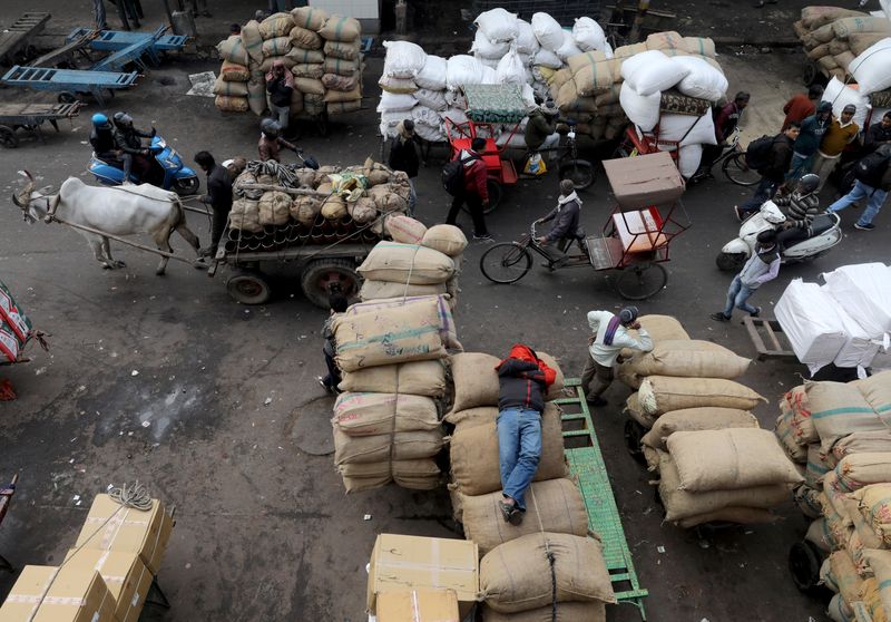 &copy; Reuters. A labourer sleeps on sacks as traffic moves past him in a wholesale market in the old quarters of Delhi