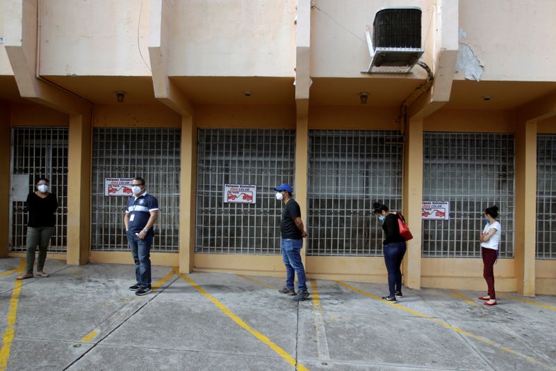 &copy; Reuters. Imagen de archivo. Personas mantienen distancia social mientras esperan para hacerse una prueba de detección del coronavirus afuera de un laboratorio en Tegucigalpa