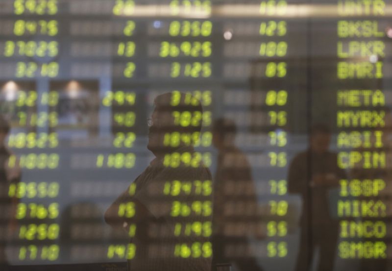 &copy; Reuters. A man stands near electronic board showing stock market index at Bank Mandiri Sekuritas trading floor in Jakarta