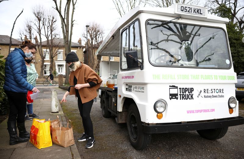 © Reuters. Ella Shone, serves a customer from her mobile zero waste shop called the 'Top Up Truck' in London