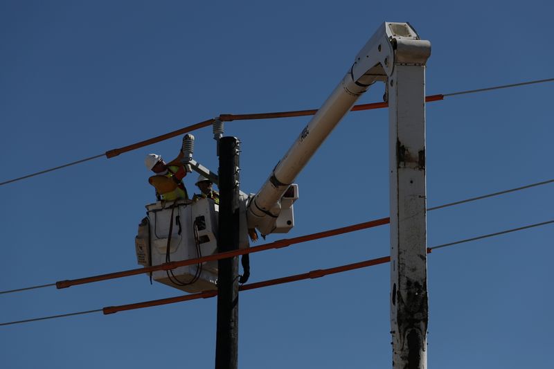 © Reuters. FILE PHOTO: Workers install a utility pole to support power lines after an unprecedented winter storm in Houston, Texas