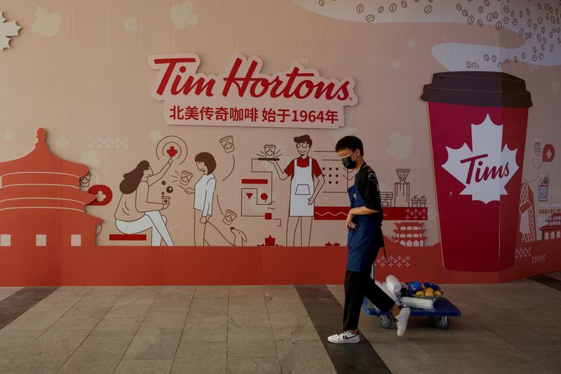 &copy; Reuters. A man walks past a store front poster advertising the opening of a cafe of the Canadian coffee and fastfood chain Tim Hortons in Beijing
