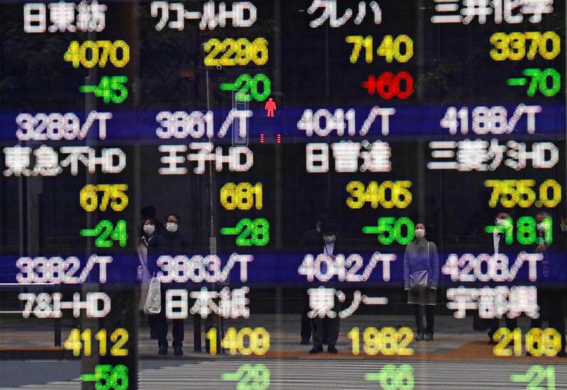 © Reuters. FILE PHOTO: Pedestrians and a traffic light stop sign are reflected on a quotation board in Tokyo