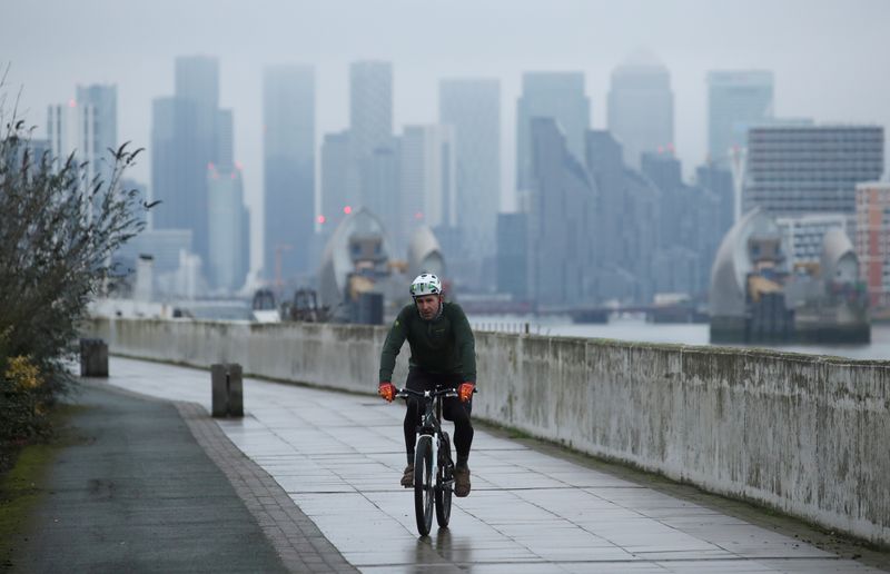 &copy; Reuters. FILE PHOTO: FILE PHOTO: Buildings are seen in the Canary Wharf business district, as a man cycles along a path, amid the outbreak of the coronavirus disease (COVID-19), in London