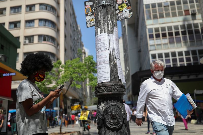 &copy; Reuters. A woman writes down on her phone a job opportunity from listings posted on a light pole in downtown Sao Paulo