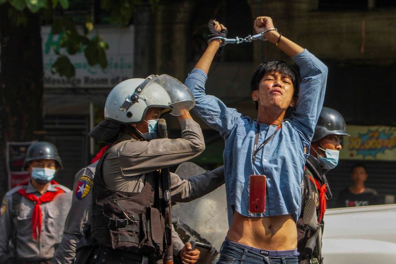 © Reuters. A pro-democracy protester is detained by riot police officers during a rally against the military coup in Yangon
