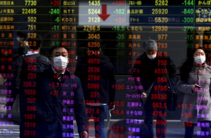 © Reuters. Pedestrians are reflected in an electronic board displaying various stock prices at a brokerage in Tokyo