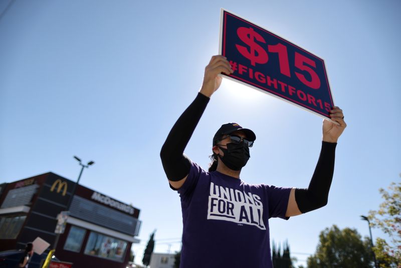 &copy; Reuters. FILE PHOTO: A man holds a minimum wage sign at a rally in California
