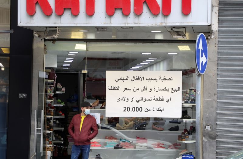 &copy; Reuters. A man stands at the entrance of a shop with a sign in Arabic reading, &quot;Liquidation for closure&quot; in Beirut