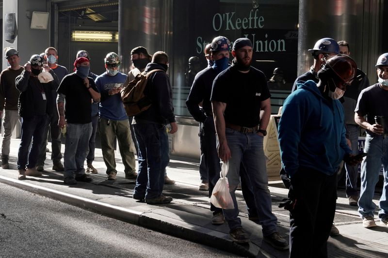 &copy; Reuters. FILE PHOTO: Construction workers wait in line to do a temperature test to return to the job site