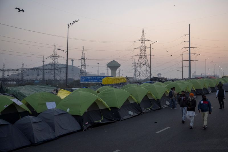 &copy; Reuters. Farmers walk outside their tents at the site of a protest against new farm laws, at the Delhi-Uttar Pradesh border in Ghaziabad