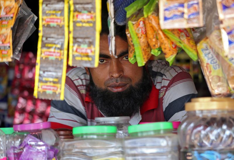 © Reuters. A man from the Rohingya community looks on as he sits inside his shop at a camp on the outskirts of Jammu