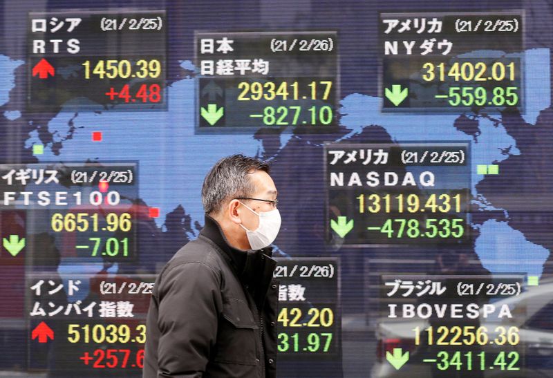 &copy; Reuters. Un uomo davanti a uno schermo a Tokyo con informazioni sugli indici delle borse mondiali