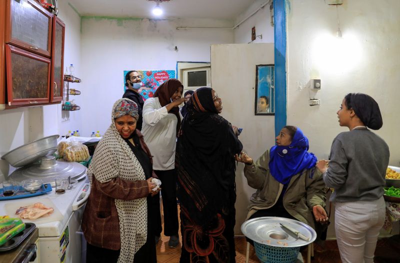 © Reuters. زوجان سودانيان يطعمان لاجئين جوعى بدعم جمعيات خيرية في مصر