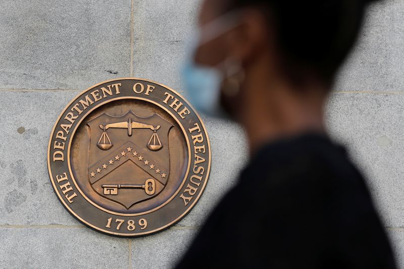 &copy; Reuters. Imagen de archivo de una persona con mascarilla pasando frente al sello del Departamento del Tesoro en la sede central de Washington, D.C., EEUU.