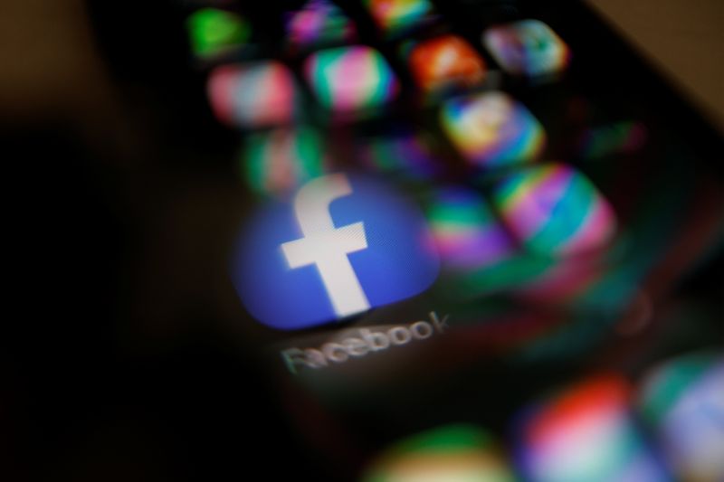 &copy; Reuters. Facebook logo displayed on a mobile phone is seen through a magnifying glass in this picture illustration