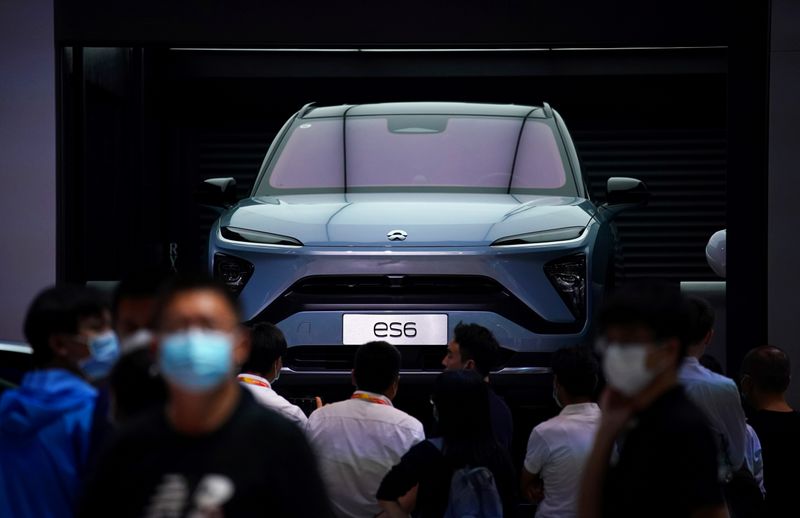 &copy; Reuters. FILE PHOTO: People wearing face masks look at a Nio ES6 EV car at the Beijing International Automotive Exhibition
