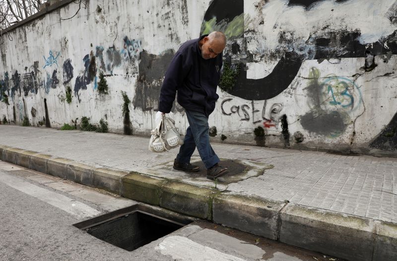 &copy; Reuters. A man walks past a manhole with a missing cover in Beirut