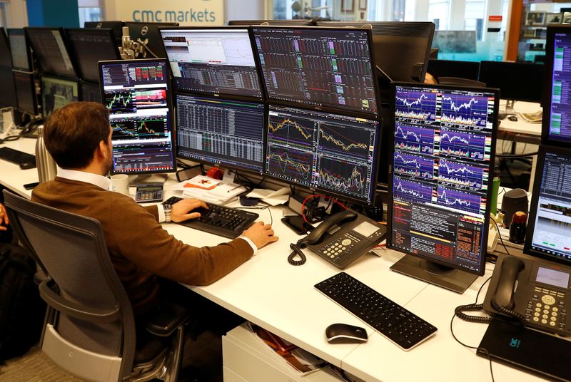 &copy; Reuters. A financial trader works at their desk at CMC Markets in the City of London