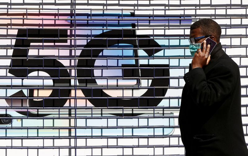 &copy; Reuters. Un hombre con una máscara pasa por delante de un anuncio de 5G durante la epidemia de coronavirus (COVID-19), Londres, Reino Unido