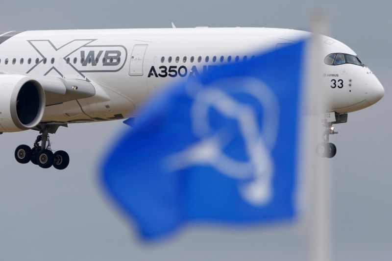 © Reuters. FILE PHOTO: An Airbus A350 flies over a Boeing flag while landing after a flying display during the 51st Paris Air Show at Le Bourget airport near Paris