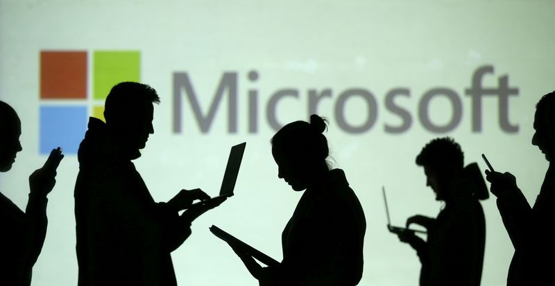 &copy; Reuters. FILE PHOTO: Silhouettes of laptop and mobile device users are seen next to a screen projection of Microsoft logo in this picture illustration