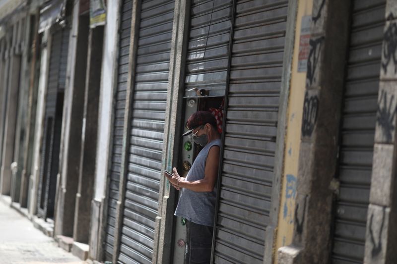 &copy; Reuters. Homem olha o celular ao lado de lojas fechadas no Rio de Janeiro