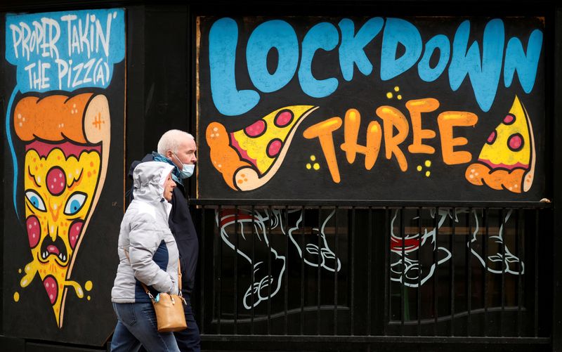 &copy; Reuters. FILE PHOTO: People walk past a mural amid the outbreak of the coronavirus disease (COVID-19) in Manchester