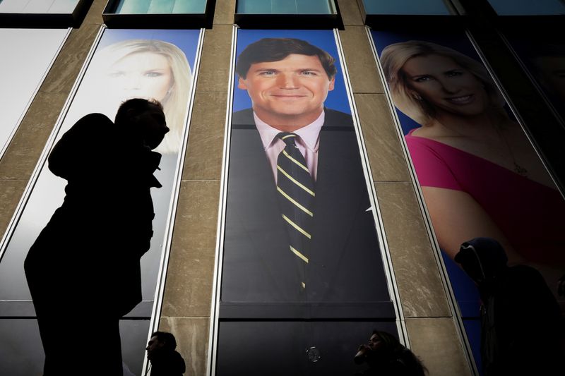 &copy; Reuters. People pass by a promo of Fox News host Tucker Carlson on the News Corporation building in New York