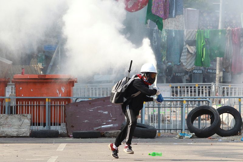 © Reuters. An anti-coup demonstrator sprays a fire extinguisher as he runs away from a barricade during a protests in Yangon