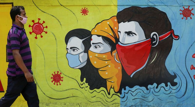 &copy; Reuters. FILE PHOTO: Man wearing a protective mask walks past a graffiti amidst the spread of COVID-19, in Navi Mumbai