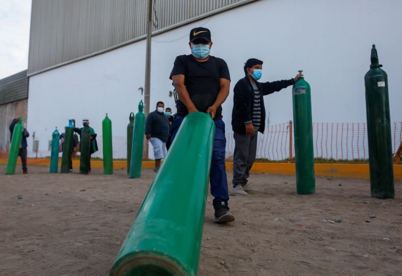 &copy; Reuters. FOTO DE ARCHIVO. Un hombre arrastra un tanque de oxígeno vacío mientras él y otros esperan para rellenarlo para pacientes que padecen la enfermedad del coronavirus (COVID-19), frente a un proveedor privado de oxígeno, en Lima, Perú.