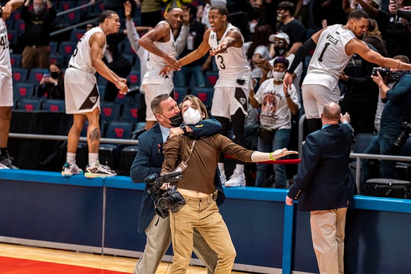 &copy; Reuters. A cameraman from the St. Bonaventure University athletic department is restrained by a security guard at UD Arena during A-10 tournament title basketball game in Dayton