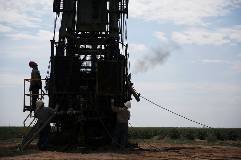 &copy; Reuters. Oil field workers prepare a swabbing rig in a cotton field in Seminole