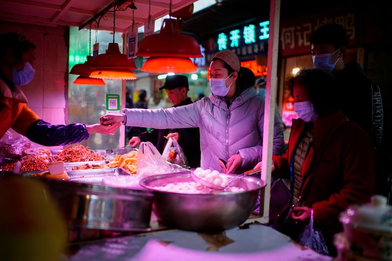 &copy; Reuters. FOTO DE ARCHIVO: Varias personas con mascarilla esperan para comprar comida en un puesto callejero de Wuhan