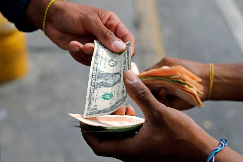 &copy; Reuters. A man changes a dollar bill with the bus driver&apos;s assistant at a bus stop outside the Antimano metro station in Caracas