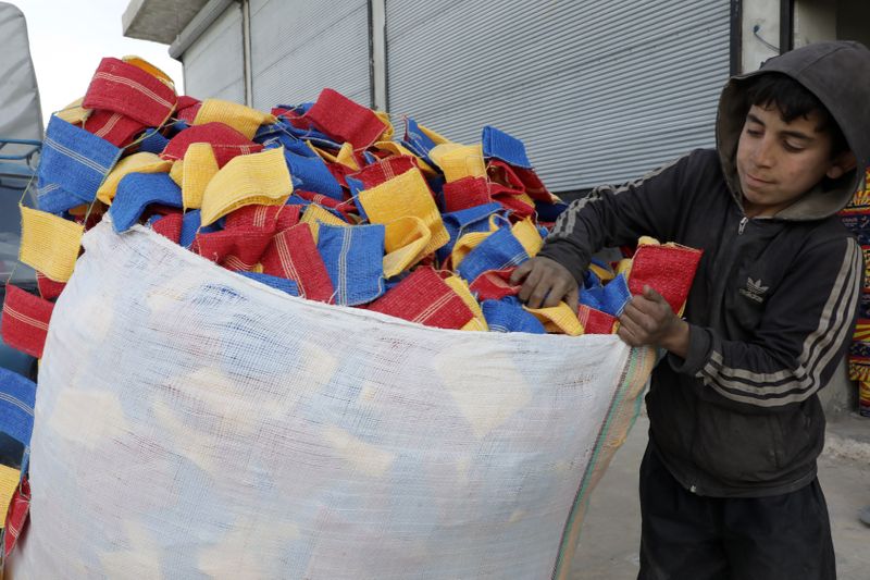 &copy; Reuters. Mohammed Abu Rdan puts dishcloths in a bag, in front of the cleaning products factory, northern Aleppo