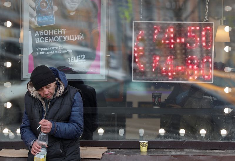 &copy; Reuters. A man smokes next to a window with a board, showing the currency exchange rates of the Euro against the Russian rouble, on a street in Moscow
